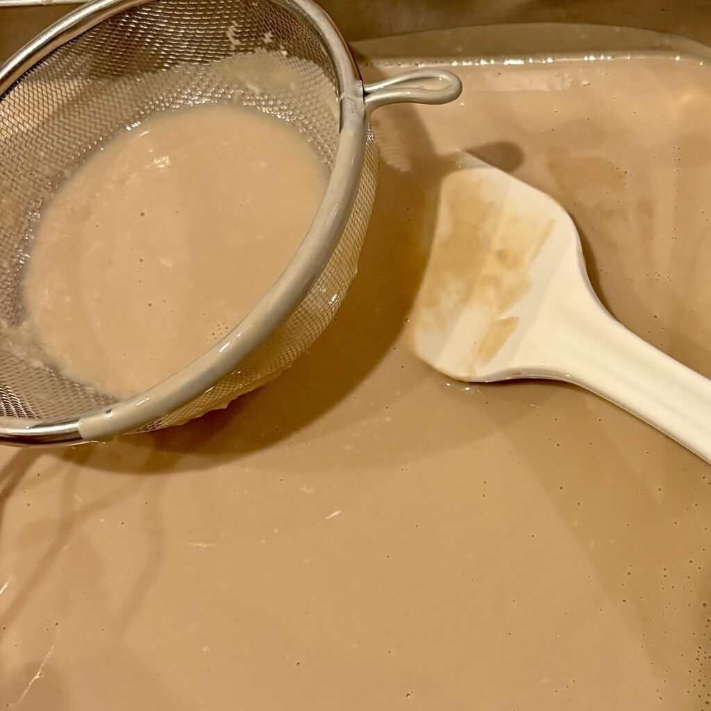 茶こしでこしながらジェラートの生地をバットへ流しているところ